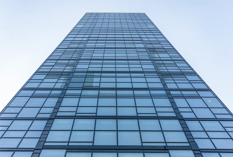 Modern glass office tower from low angle showing building facade with reflective curtain wall